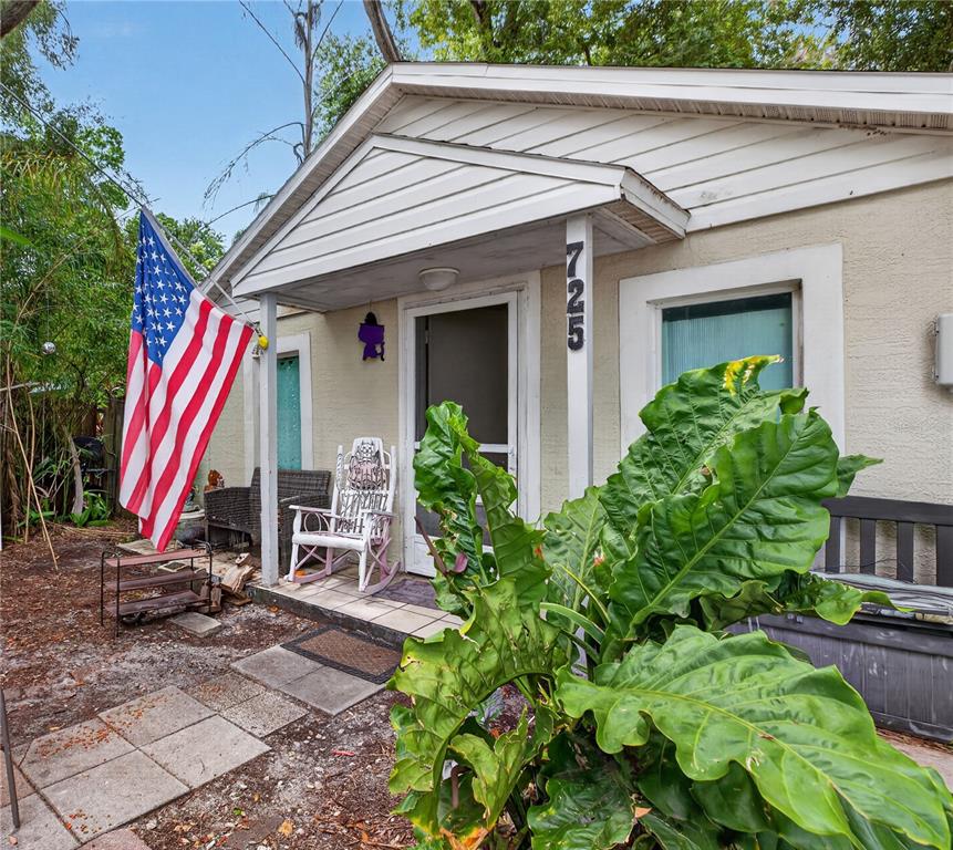 A small house exterior features a front porch with a rocking chair and American flag — 725 NEW YORK ST, CLEARWATER, FL