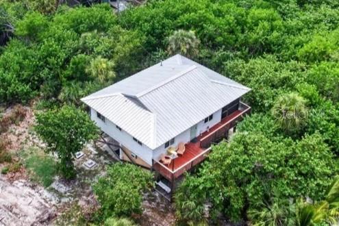 An aerial view shows a white house with a metal roof surrounded by dense trees — 9602 DOUBLOON TRAIL, PLACIDA, FL