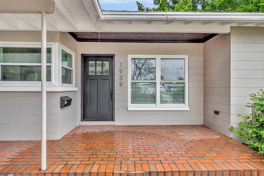 A front porch with a brick floor leads to a black door and a window — 1939 GUNN ROAD, WINTER PARK, FL