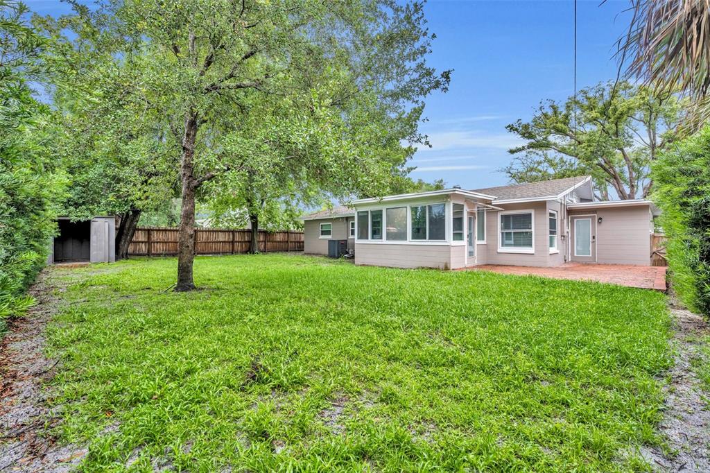 A backyard view of a house with a sunroom, brick patio, and a storage shed — 1939 GUNN ROAD, WINTER PARK, FL