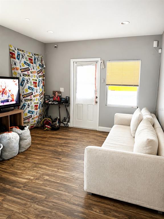 A living room features a beige sofa, a television, a door, and wood-look flooring — 1604 ANGLE ROAD, FORT PIERCE, FL