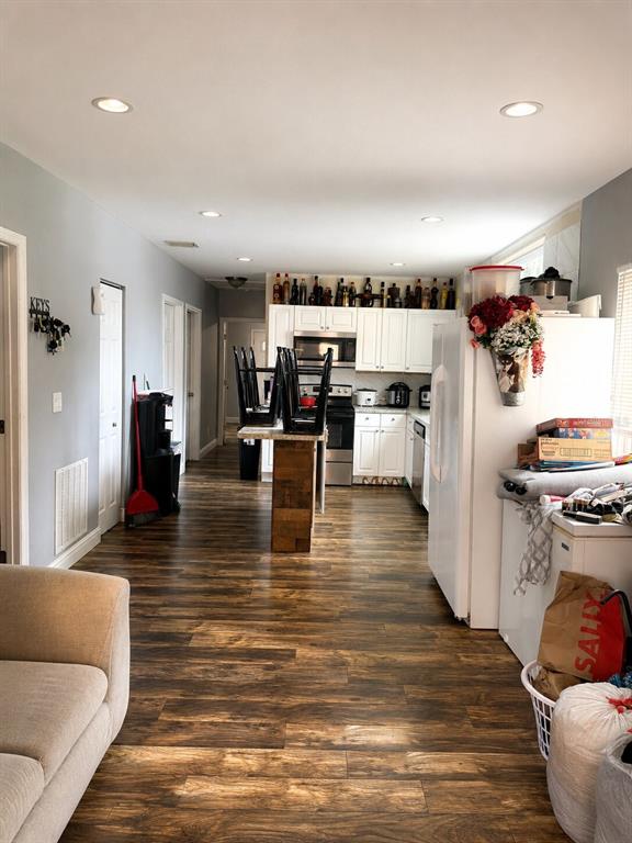 A kitchen with white cabinets and wood-look flooring opens into a living area — 1604 ANGLE ROAD, FORT PIERCE, FL