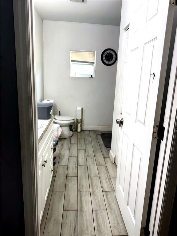 A bathroom features light wood-look tile flooring, a white vanity, and a toilet — 1604 ANGLE ROAD, FORT PIERCE, FL