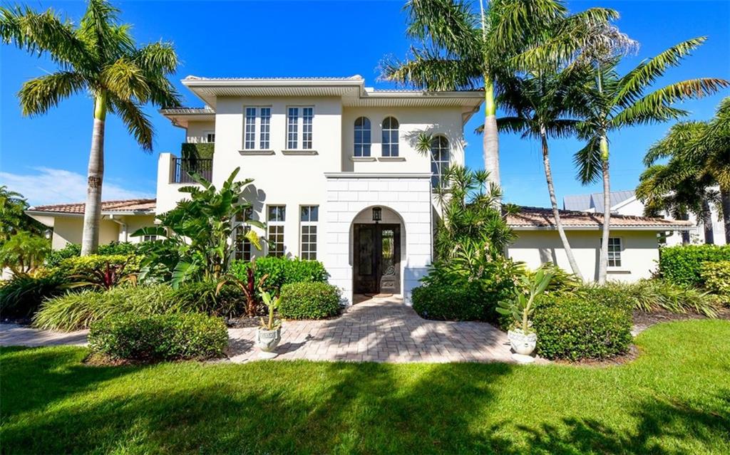 A two-story stucco house with a tiled roof, arched entryway, and palm trees in the yard — 1179 MORNINGSIDE PLACE, SARASOTA, FL