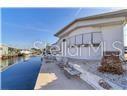 A white house sits along a narrow canal with a concrete patio and outdoor seating — 6916 E BAYOU LANE, BRADENTON, FL