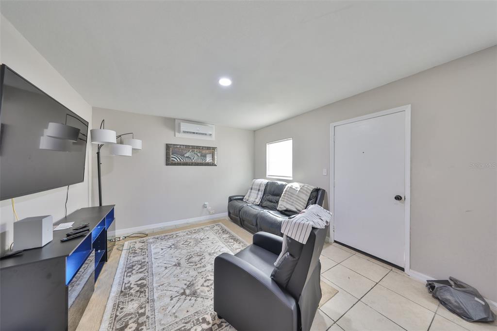 A living room features tile flooring, a black leather sofa, a recliner, and a television — 11708 BALM RIVERVIEW ROAD, RIVERVIEW, FL