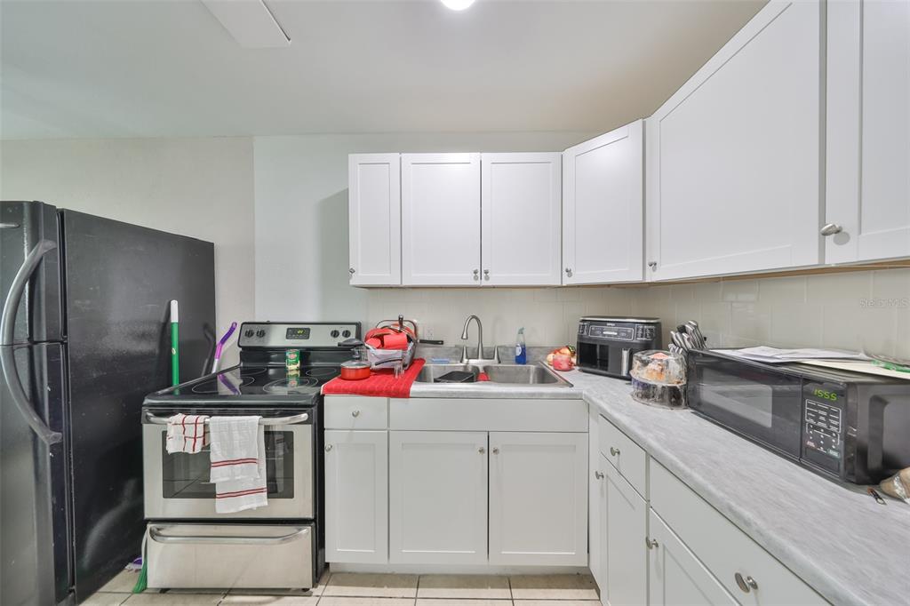A kitchen features white cabinets, stainless steel appliances, a double sink, and light countertops — 11708 BALM RIVERVIEW ROAD, RIVERVIEW, FL