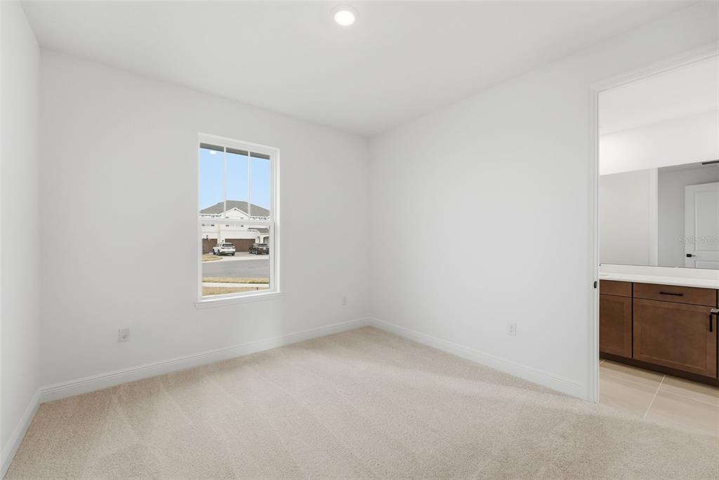 A carpeted bedroom with white walls, a single window, and an attached bathroom — 3500 LEMON BUTTON TERRACE, APOPKA, FL
