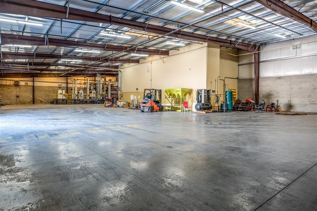 A large industrial warehouse space features a concrete floor, exposed steel beams, and various equipment — 1770 BUSINESS CENTER LANE, KISSIMMEE, FL