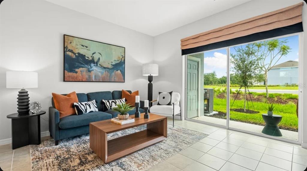 A living room features a blue sofa, a wooden coffee table, and a sliding glass door — 671 NESS ISLAND DRIVE UNIT 0, MOUNT DORA, FL