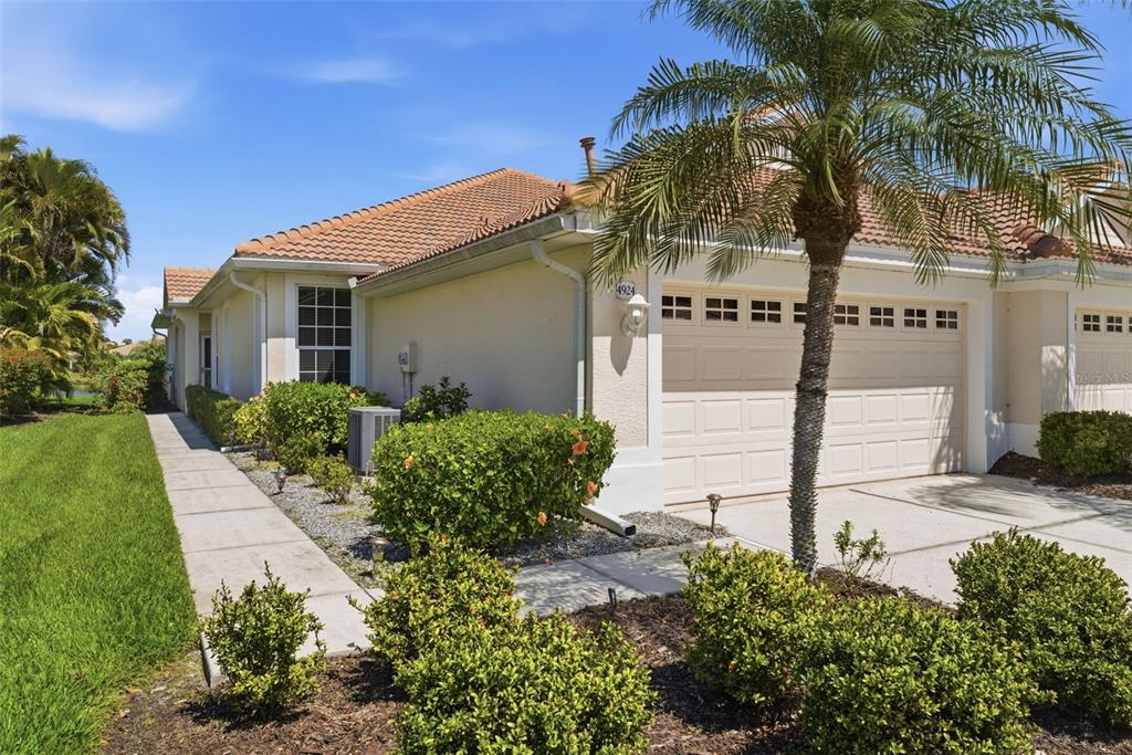 A single-story house with a tiled roof, a two-car garage, and landscaped front yard — 4924 WHISPERING OAKS DRIVE, NORTH PORT, FL