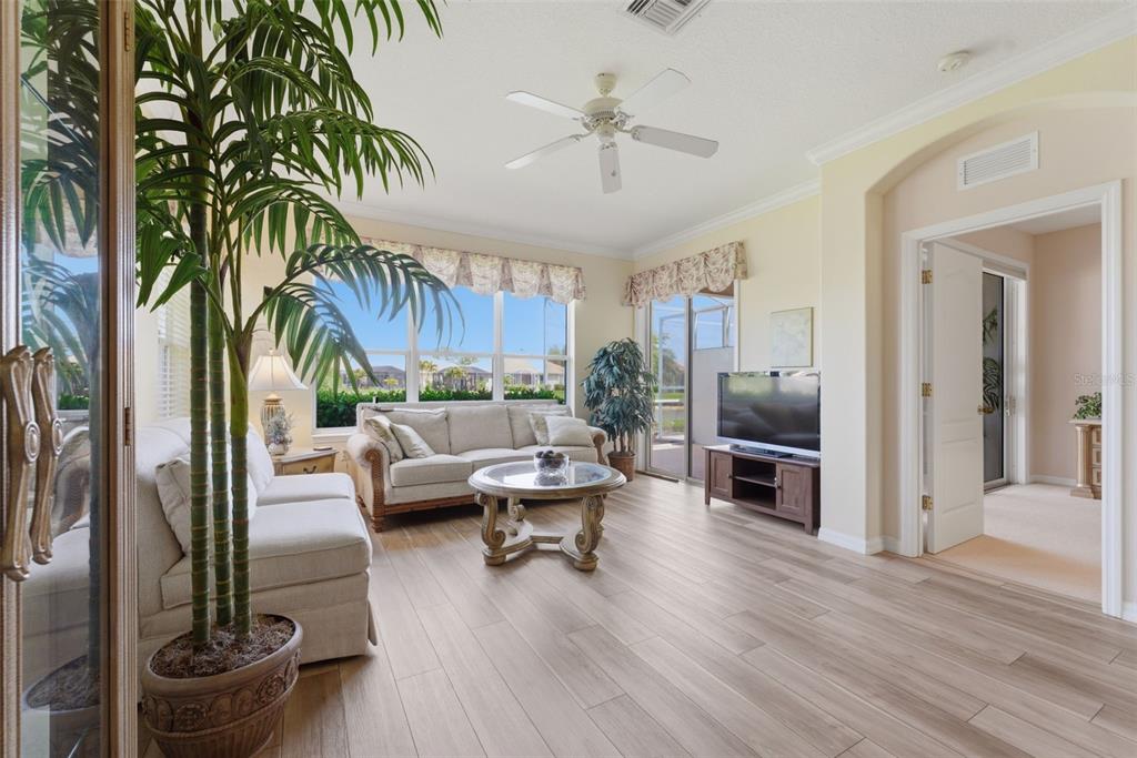 A living room with light wood floors, a sofa, a coffee table, and a ceiling fan — 4924 WHISPERING OAKS DRIVE, NORTH PORT, FL