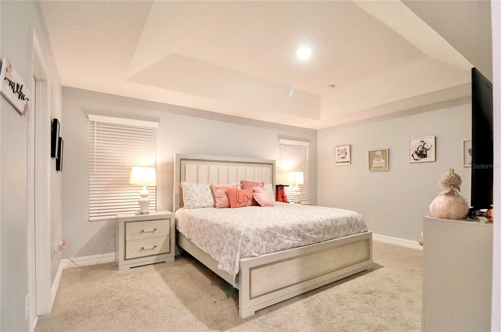A bedroom features a tray ceiling, a light-colored bed frame, and two bedside lamps — 2280 AVIAN LOOP, KISSIMMEE, FL