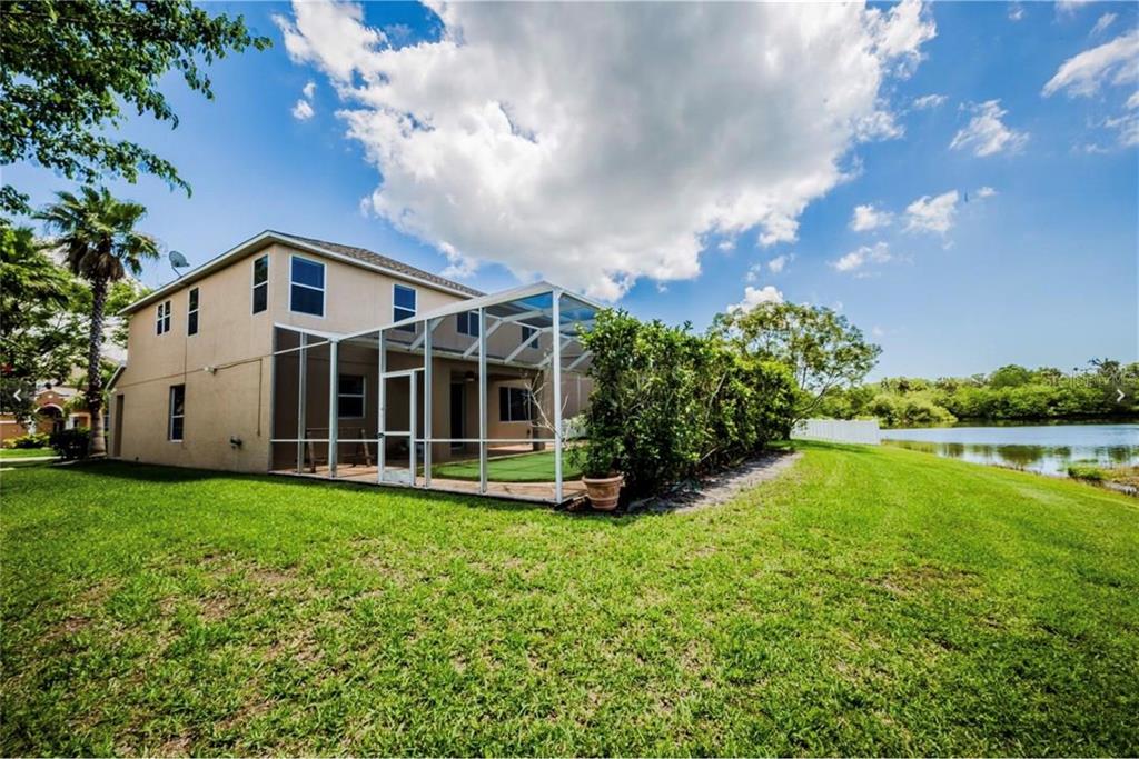 A two-story house with a screened-in patio overlooking a lake and grassy yard — 6006 BROAD RIVER RUN, ELLENTON, FL