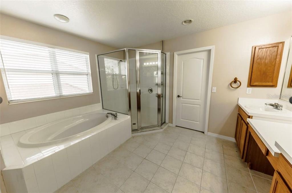 A bathroom features a soaking tub, a corner glass shower, and a wooden vanity — 6006 BROAD RIVER RUN, ELLENTON, FL