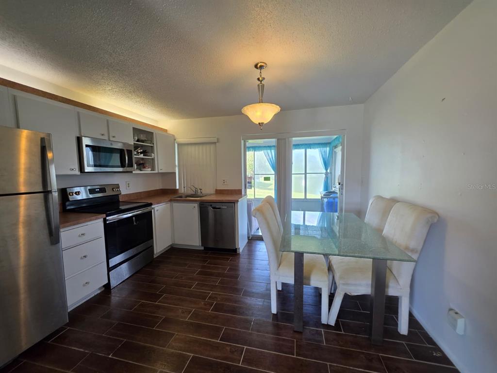 A living room with dark wood-look tile flooring, a large white sectional, and teal wall — 3765 101ST AVENUE N UNIT -, PINELLAS PARK, FL