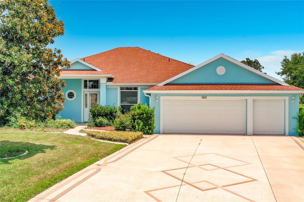 A light blue single-story house features a red roof and a three-car garage — 4632 NOTTOWAY, LEESBURG, FL