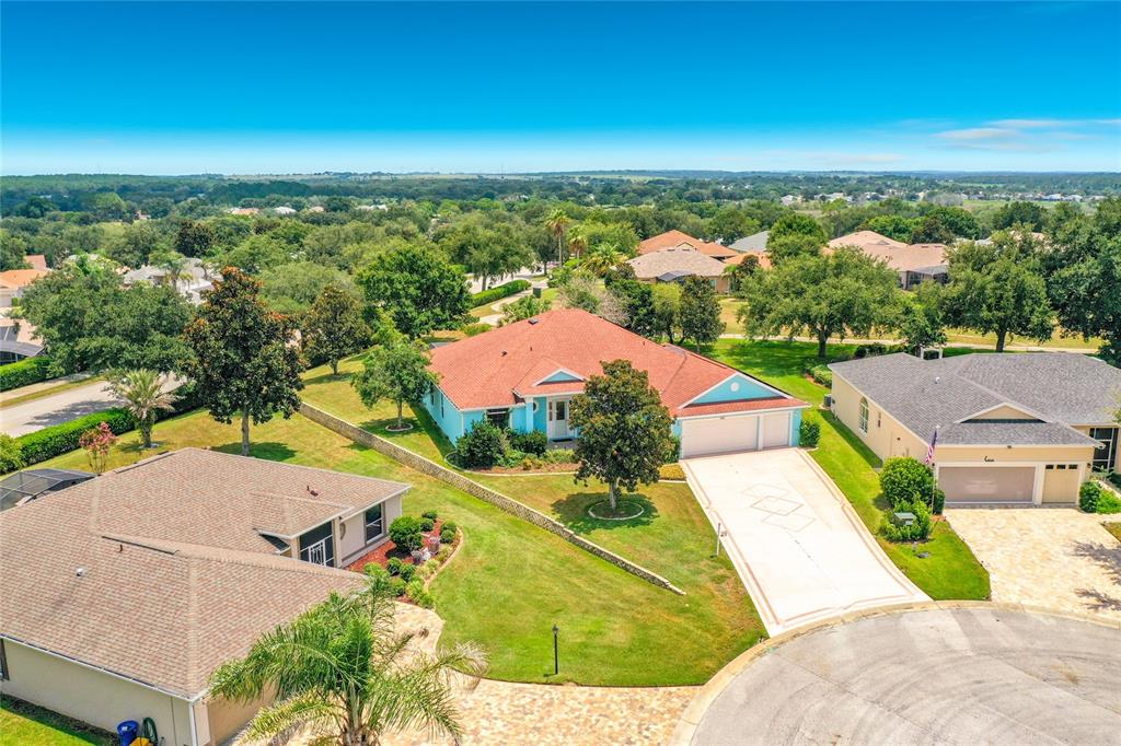 An aerial view shows a light blue house with a red roof and driveway — 4632 NOTTOWAY, LEESBURG, FL