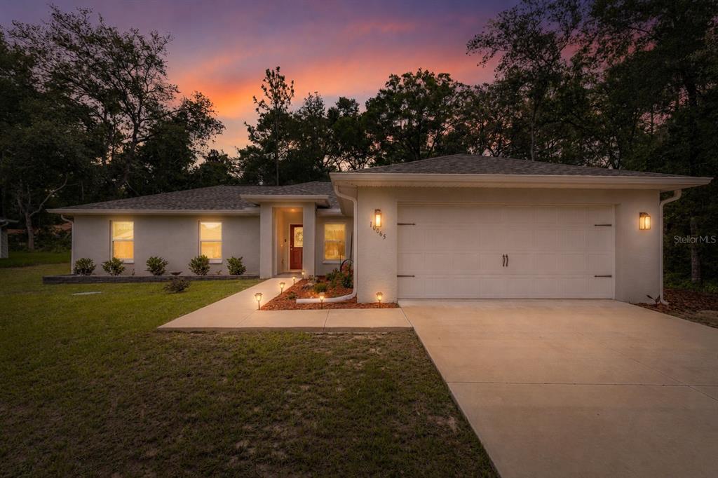 An aerial view of a single-story house with a driveway and a sunset sky background — 10065 N LANGDON ROAD, CITRUS SPRINGS, FL