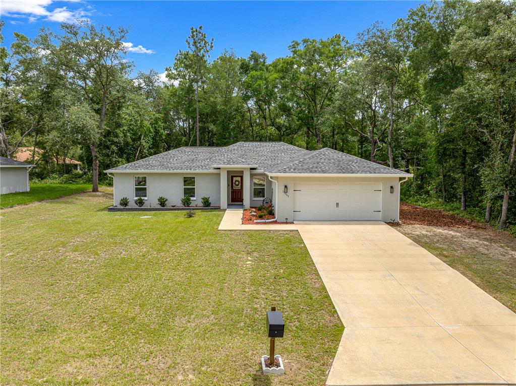 A single-story house with a white stucco exterior, a two-car garage, and a landscaped yard — 10065 N LANGDON ROAD, CITRUS SPRINGS, FL