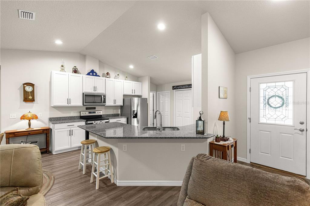 An open-concept living room and kitchen with wood-look flooring, vaulted ceilings, and a sliding door — 10065 N LANGDON ROAD, CITRUS SPRINGS, FL
