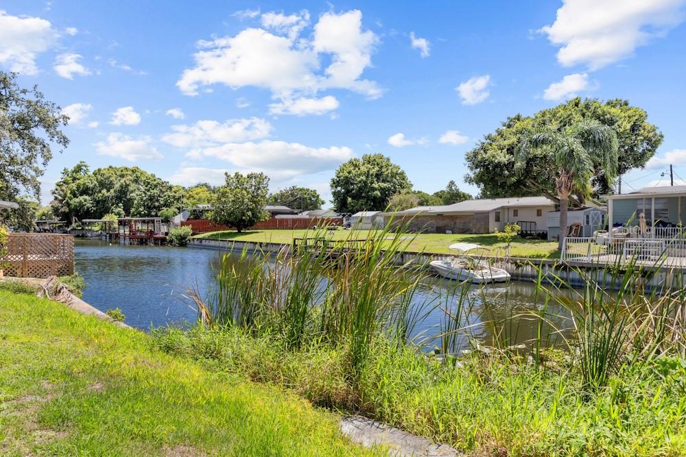 A canal view showing a grassy backyard, a small boat, and neighboring houses — 2809 SE 38TH AVENUE, OKEECHOBEE, FL