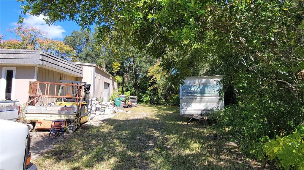 An outdoor area features a building, a forklift, a trailer, and dense surrounding trees — LAKEVIEW STREET, DELAND, FL