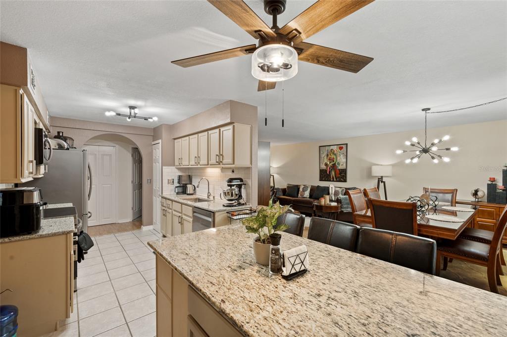 A kitchen with granite countertops and an island overlooks an open-concept dining and living area — 100 E OAK TERRACE DRIVE UNIT A2, LEESBURG, FL