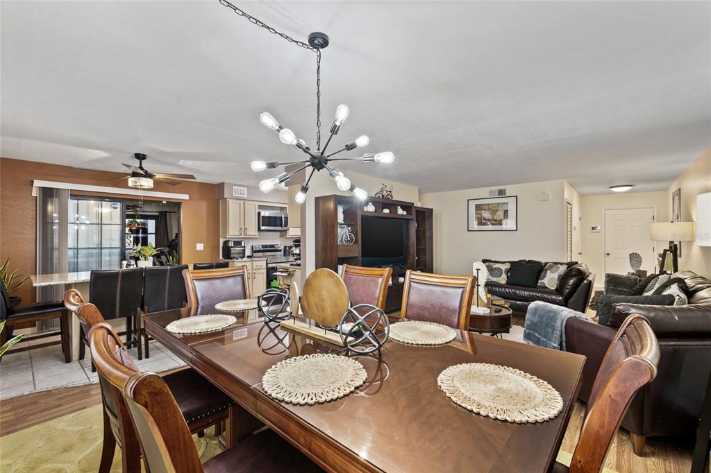 A dining area with a wooden table and chandelier opens into a living room and kitchen — 100 E OAK TERRACE DRIVE UNIT A2, LEESBURG, FL