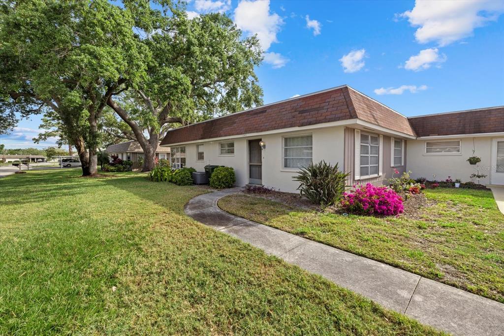 A single-story residential building with a brown shingled roof, white walls, and a curved walkway — 1343 GLENDALE CIRCLE W UNIT 216, SARASOTA, FL