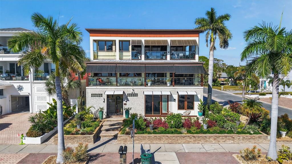 A three-story house with balconies, large windows, and palm trees in the front yard — 5659 SHORE BOULEVARD S, GULFPORT, FL