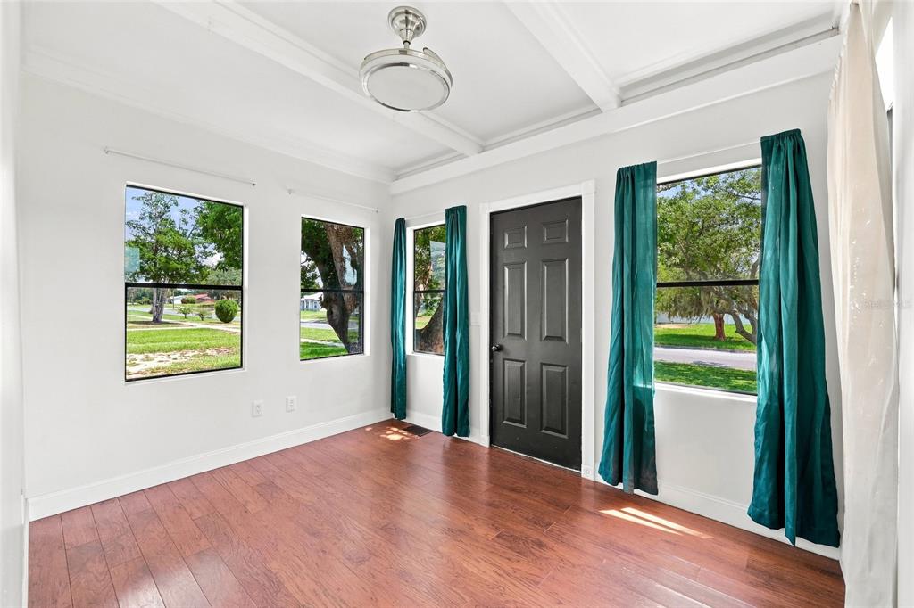 A sunroom with wood-look flooring, white walls, a black door, and teal curtains — 4 E BAY STREET, DAVENPORT, FL