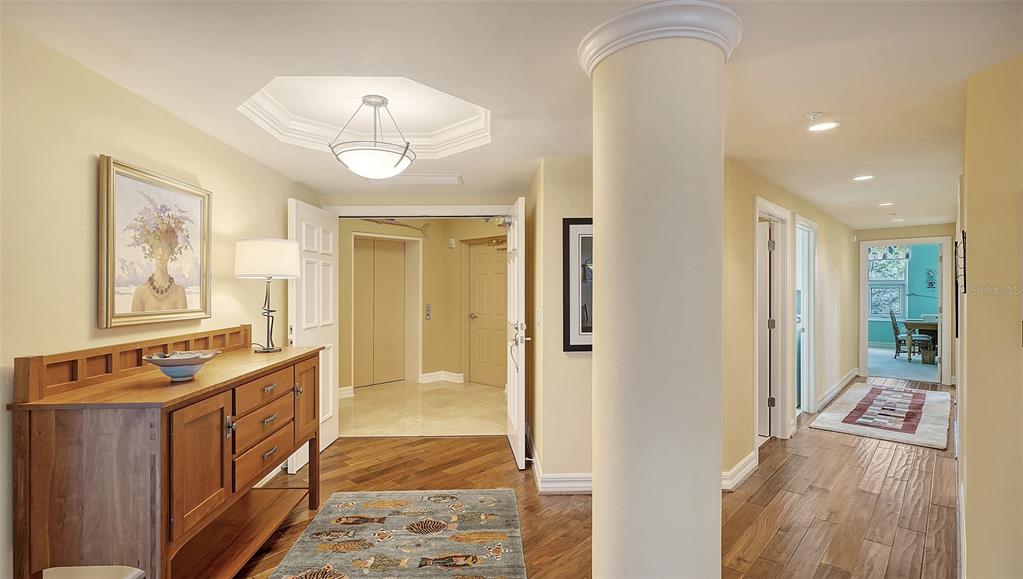 A foyer with wood flooring, a central column, and a wooden console table — 3621 N POINT ROAD UNIT 301, OSPREY, FL