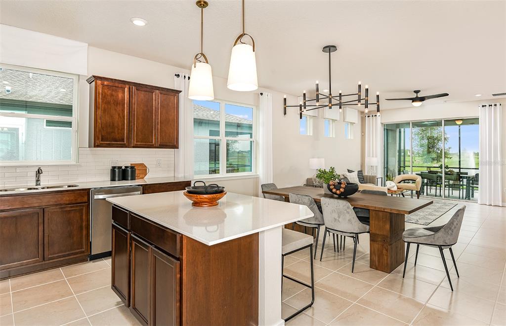 A kitchen with dark wood cabinets, a white island, and an adjacent dining area — 12510 ADOBE STREET, PARRISH, FL