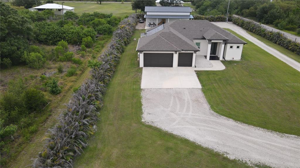 An aerial view shows a single-story house with a three-car garage and a gravel driveway — 8279 ALFRED BOULEVARD, PUNTA GORDA, FL
