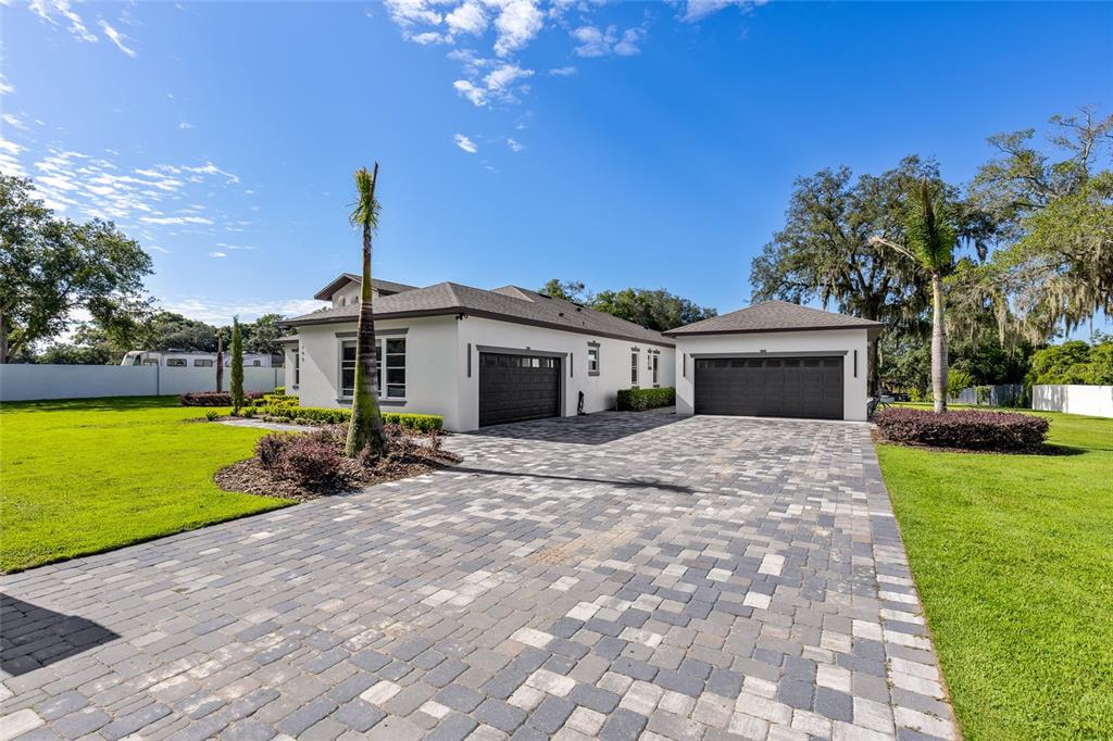 A single-story house with a paved driveway and two separate garage doors under a blue sky — 1924 HILL DRIVE, APOPKA, FL