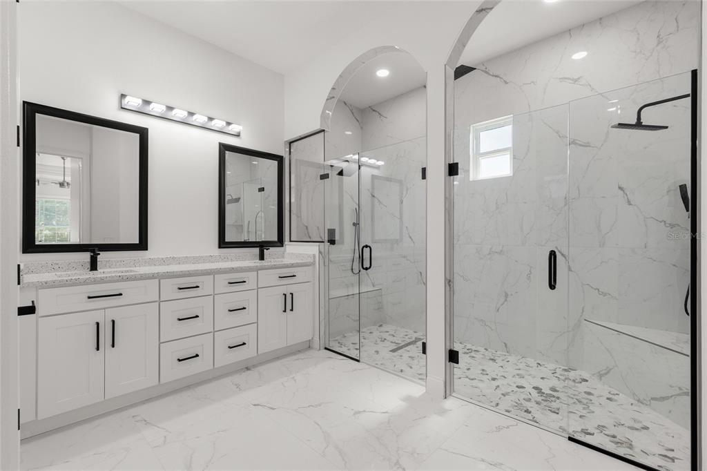 A modern bathroom features a double vanity with black-framed mirrors and a large glass-enclosed shower — 1924 HILL DRIVE, APOPKA, FL