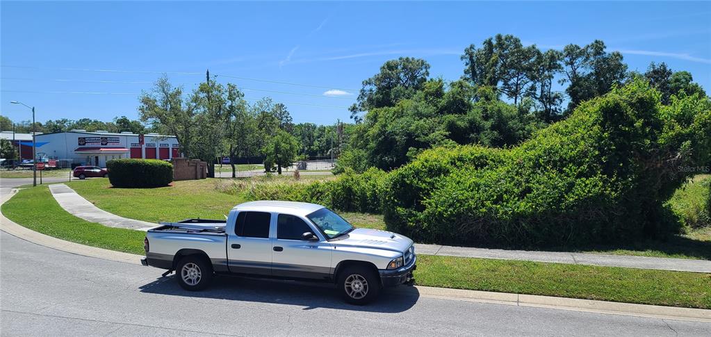 A silver pickup truck is parked on a street next to a vacant, overgrown lot — 0 WOOD DOVE AVENUE, TARPON SPRINGS, FL
