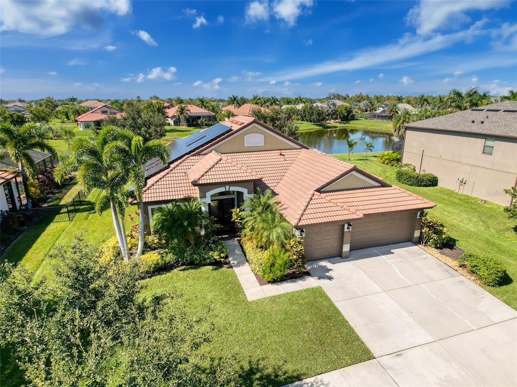 An aerial view of a single-story house with a tile roof, solar panels, and driveway — 335 COCKLE SHELL LOOP, APOLLO BEACH, FL