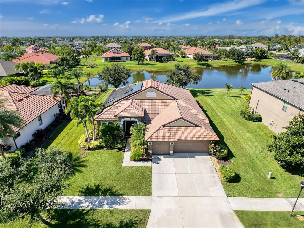 An aerial view of a suburban house with a tile roof, solar panels, and driveway — 335 COCKLE SHELL LOOP, APOLLO BEACH, FL