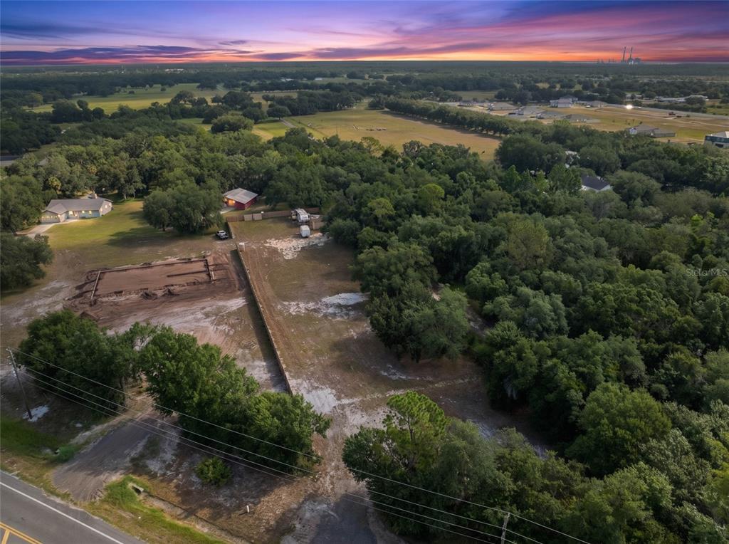An aerial view shows a cleared residential lot with a foundation under construction at sunset — 15580 COUNTY ROAD 675, PARRISH, FL