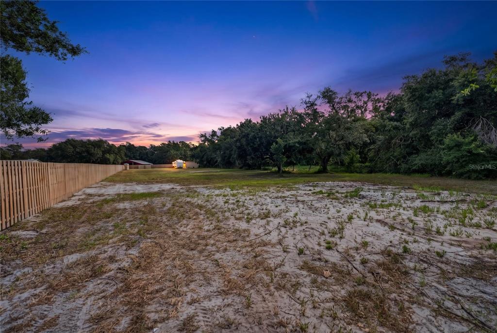 A large, sandy, undeveloped lot features a wooden fence and trees under a sunset sky — 15580 COUNTY ROAD 675, PARRISH, FL