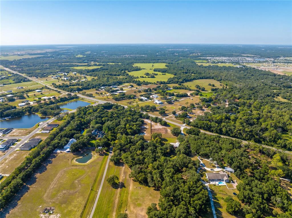 An aerial view shows a rural landscape with scattered houses, wooded areas, and small ponds — 15580 COUNTY ROAD 675, PARRISH, FL