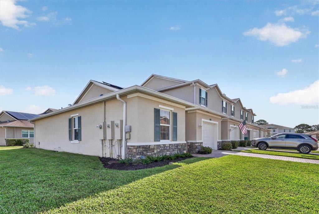 A side view of a beige two-story townhouse with stone accents and a paved driveway — 968 NE TRAILSIDE RUN, PORT ST LUCIE, FL