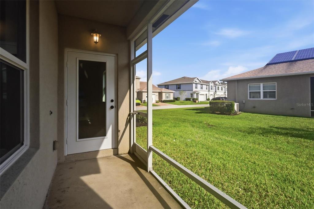 A covered screened-in porch overlooks a grassy backyard and neighboring suburban houses — 968 NE TRAILSIDE RUN, PORT ST LUCIE, FL