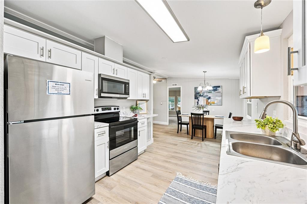 An open-concept kitchen and living area with light wood flooring and white cabinetry — 2055 S FLORAL AVENUE UNIT 117, BARTOW, FL