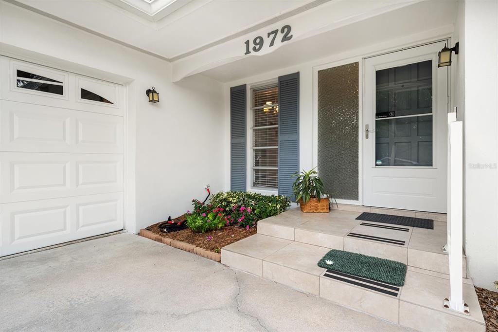 The exterior of a house features a white garage door, a front door, and tiled steps — 1972 SEVER DRIVE, CLEARWATER, FL