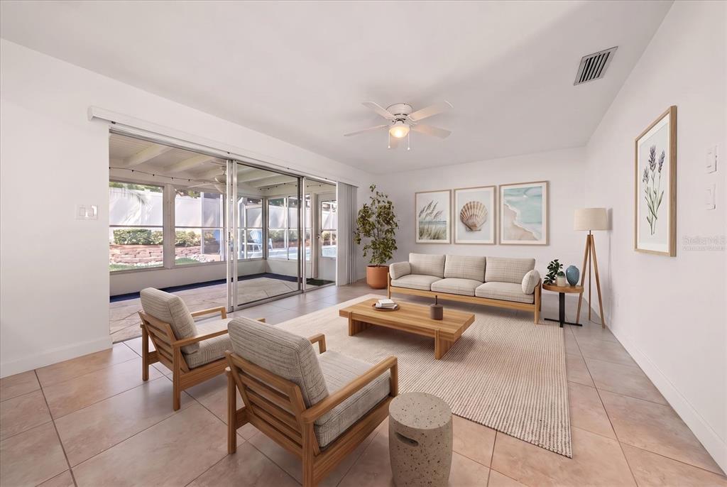 A bright living room features tile floors, a sofa, two armchairs, and sliding glass doors — 1972 SEVER DRIVE, CLEARWATER, FL