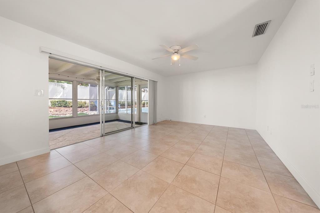 An empty room with light-colored tile flooring, a ceiling fan, and sliding glass doors — 1972 SEVER DRIVE, CLEARWATER, FL