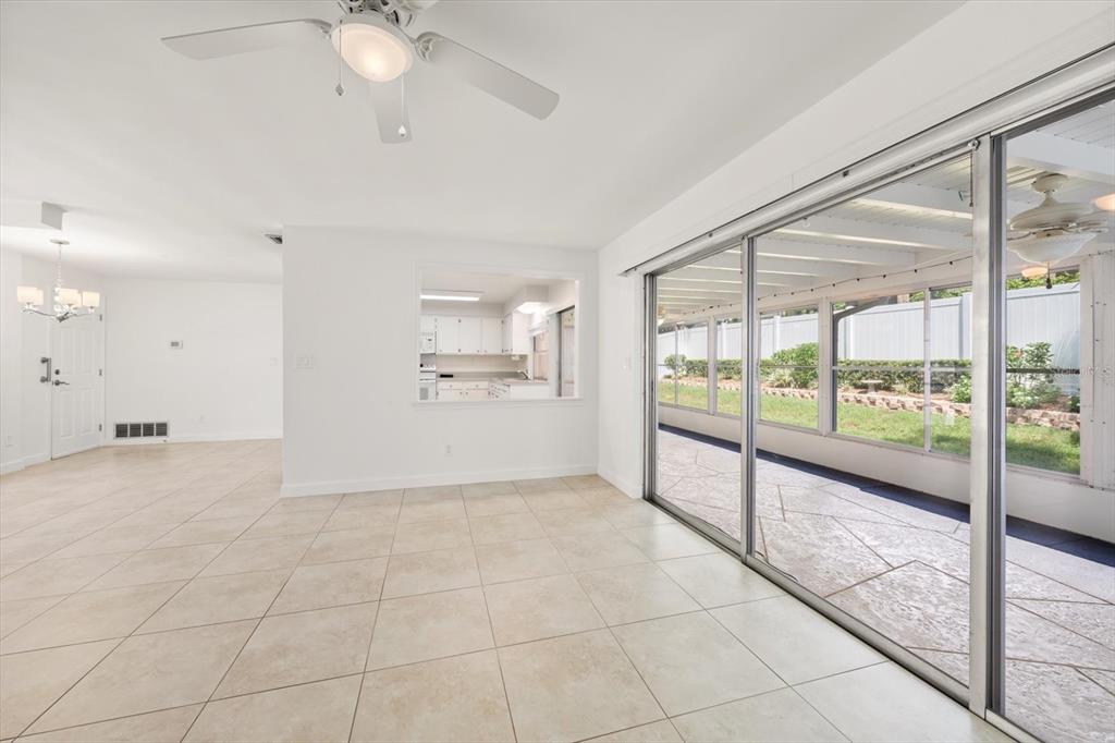 A bright living room with tile floors, a ceiling fan, and sliding doors to a patio — 1972 SEVER DRIVE, CLEARWATER, FL
